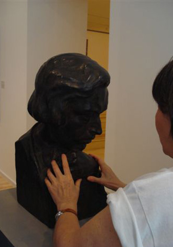 Daniela Bottegoni esplora tattilmente una scultura in bronzo (busto)