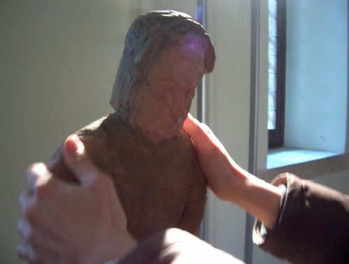 Mani che toccano la scultura Nonna del sud di Tagliaferri