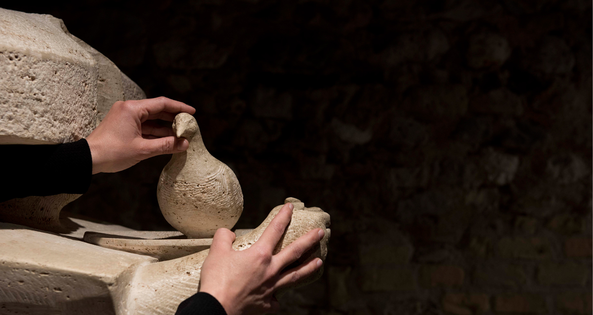 mani che toccano particolare opera originale in marmo travertino Stele delle colombe di Girolamo Ciulla