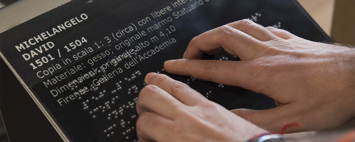 mani che leggono una targa scritta in Braille