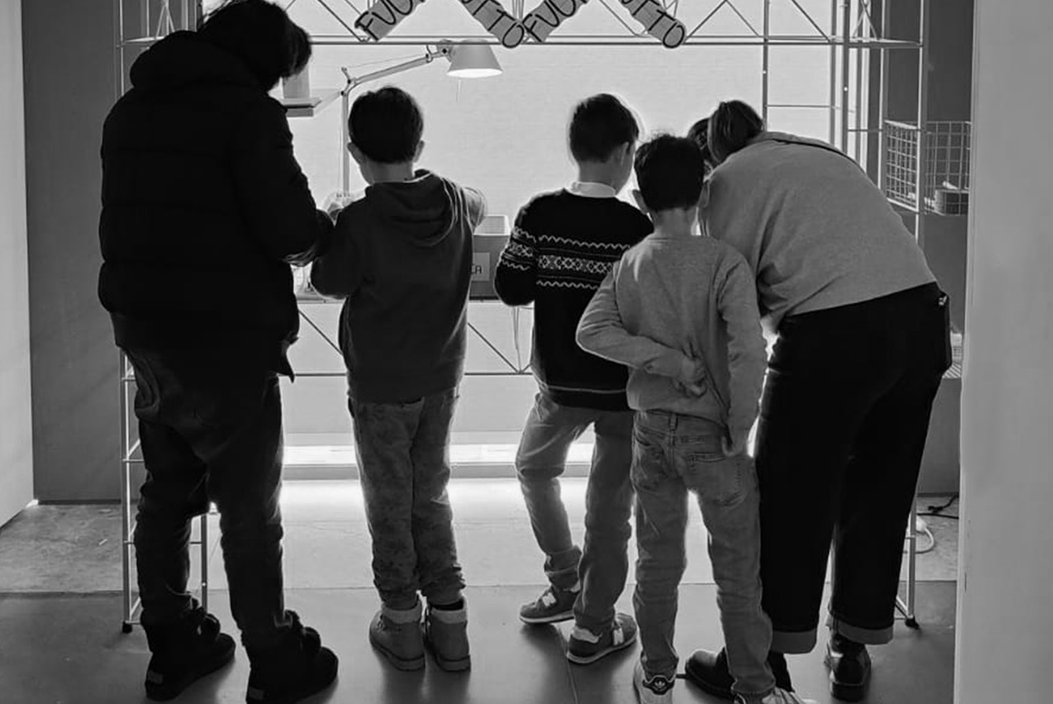 A family with their backs to the viewer is engaged with Bruno Munari's artwork "Abitacolo."