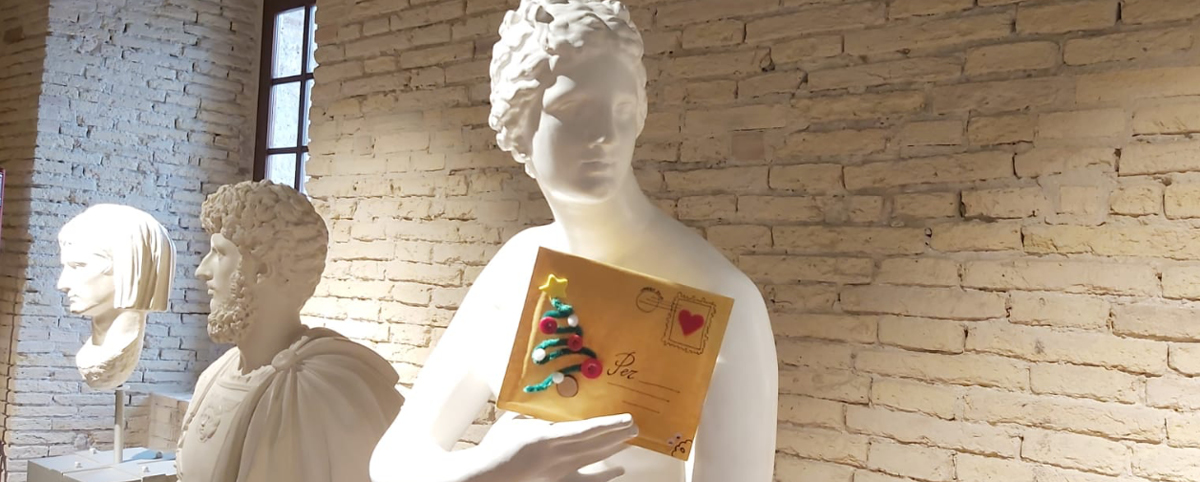Una statua regge in mano un biglietto di auguri di Natale