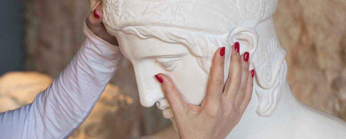 Mani accarezzano il volto del busto di Ares Borghese
