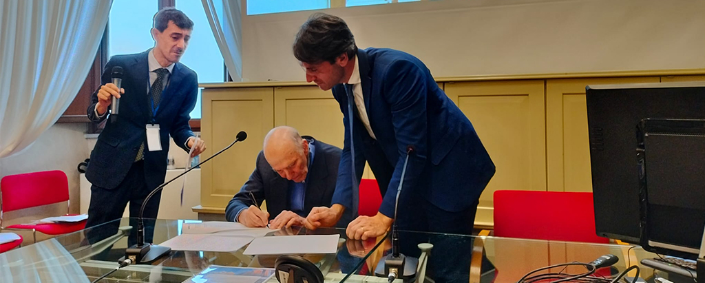 President Aldo Grassini signs the agreement