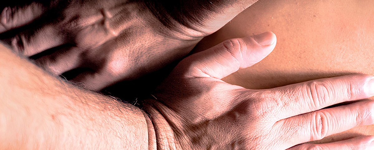 Particolare della copertina del libro: due mani appoggiate e intrecciate su una superficie nuda, nell’atto di un contatto delicato e attento.